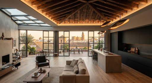 Ático reformado en el centro histórico de Málaga con vigas de madera restauradas, suelo de roble blanqueado y cocina abierta con isla.